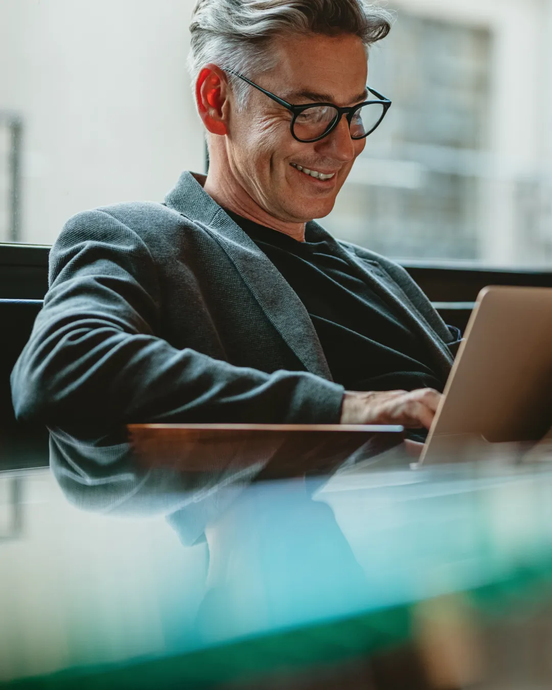 waldine_consulting-organisationsutveckling_ledarskapsutveckling Man i kostym och glasögon jobbar skriver en bärbar dator. Waldine Consulting - Chefsstöd